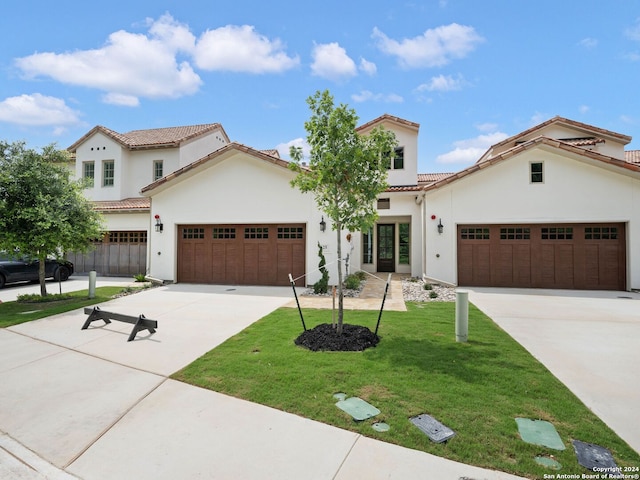 mediterranean / spanish-style house with a garage and a front lawn