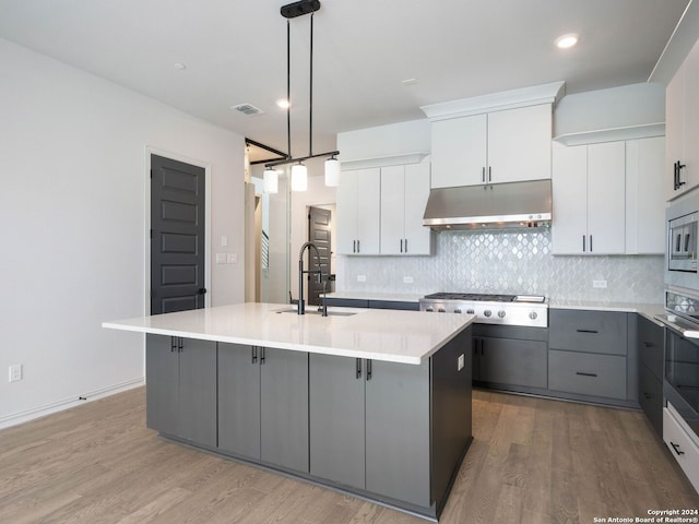 kitchen with hanging light fixtures, a center island with sink, gray cabinetry, hardwood / wood-style flooring, and sink