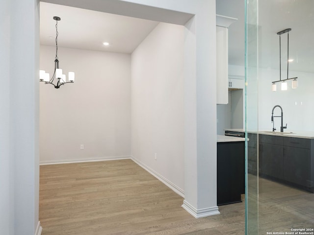 corridor featuring wood-type flooring, sink, and a chandelier