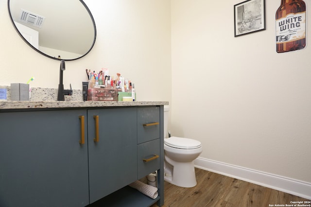 bathroom with wood-type flooring, vanity, and toilet