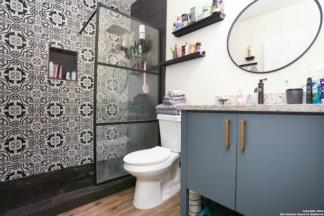 bathroom with a shower with shower door, hardwood / wood-style flooring, vanity, and toilet