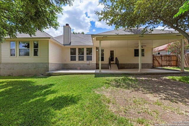 rear view of property with ceiling fan, a yard, and a patio