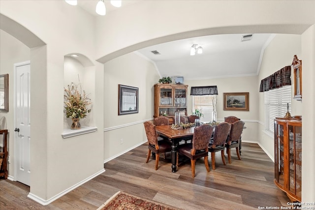 dining area featuring lofted ceiling, hardwood / wood-style floors, and crown molding