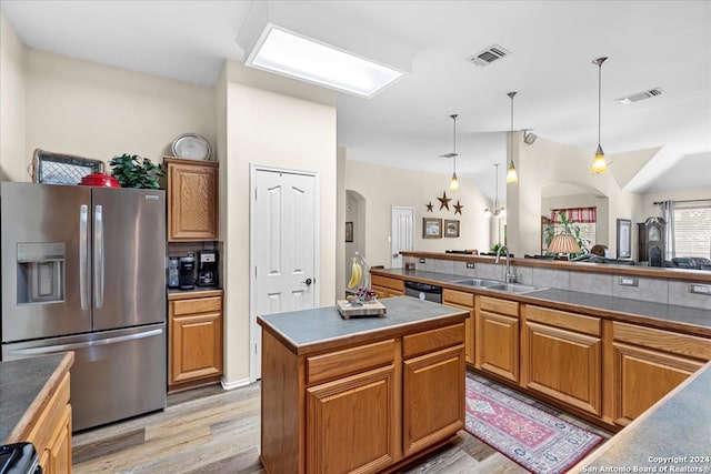 kitchen with a kitchen island, hanging light fixtures, appliances with stainless steel finishes, light hardwood / wood-style floors, and sink