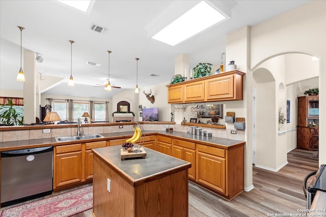 kitchen with stainless steel dishwasher, sink, light wood-type flooring, kitchen peninsula, and ceiling fan