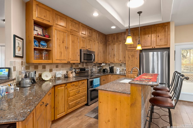 kitchen featuring appliances with stainless steel finishes, sink, tasteful backsplash, and an island with sink