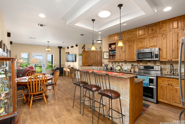 kitchen featuring a breakfast bar, pendant lighting, light wood-type flooring, and stainless steel appliances