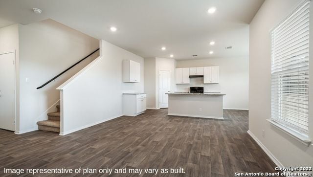 kitchen with white cabinets, a kitchen island, dark wood-type flooring, and black range oven