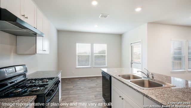 kitchen with black appliances, sink, white cabinetry, and hardwood / wood-style floors