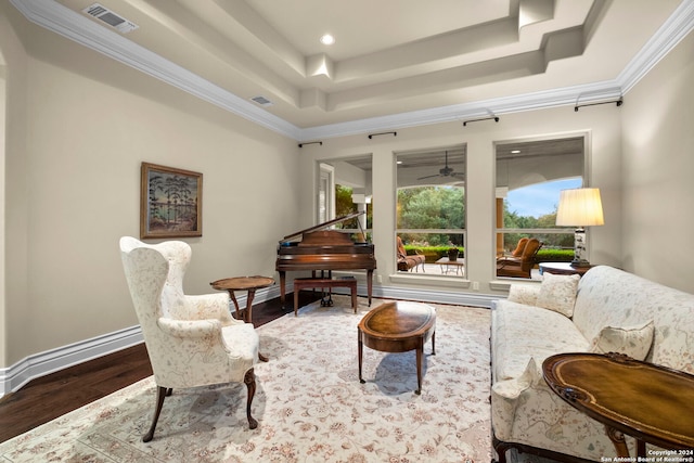 living room featuring a tray ceiling, wood-type flooring, crown molding, and ceiling fan