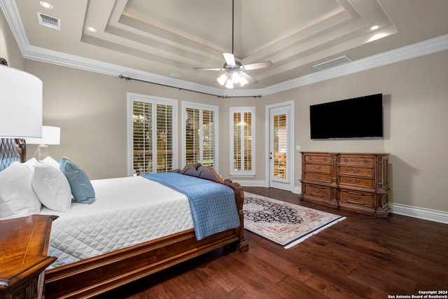 bedroom featuring ceiling fan, a tray ceiling, ornamental molding, and dark wood-type flooring