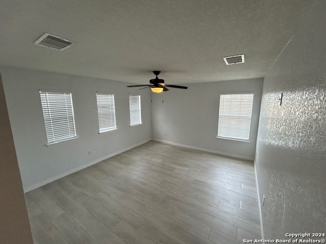 empty room featuring ceiling fan, a textured ceiling, and wood-type flooring