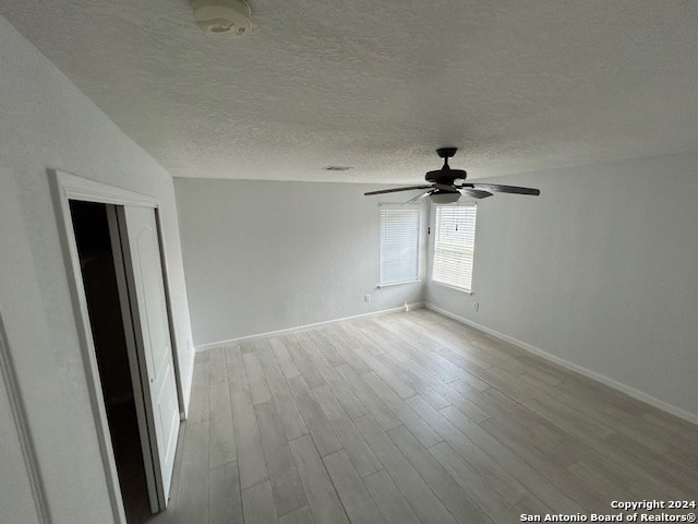 empty room featuring ceiling fan, hardwood / wood-style flooring, and a textured ceiling