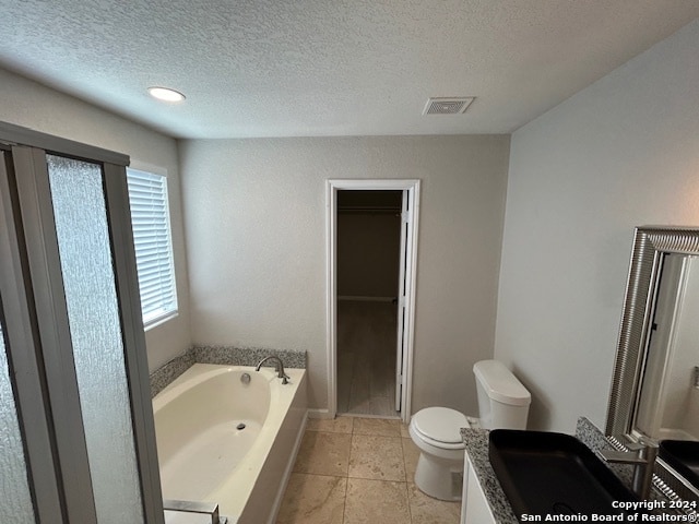 bathroom with tile flooring, toilet, a textured ceiling, and a bathing tub