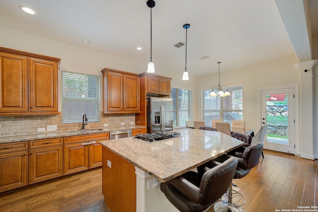 kitchen featuring a kitchen island, stainless steel appliances, hardwood / wood-style flooring, pendant lighting, and tasteful backsplash