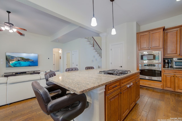 kitchen with appliances with stainless steel finishes, a kitchen bar, and hardwood / wood-style floors