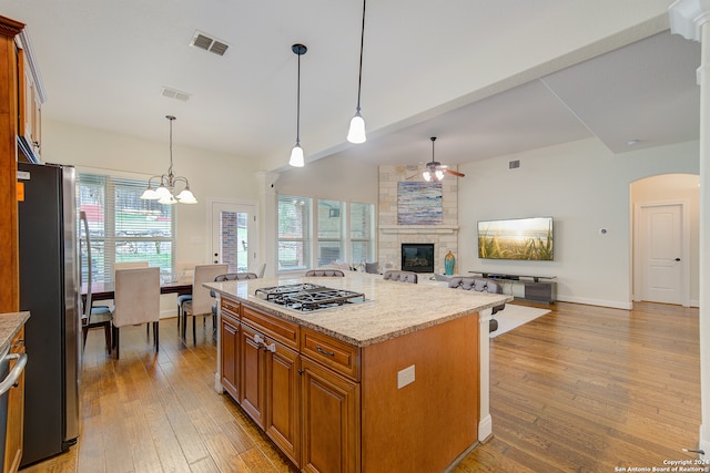 kitchen featuring a fireplace, pendant lighting, light hardwood / wood-style flooring, and stainless steel appliances