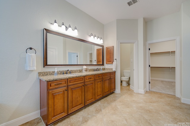 bathroom with tile flooring, vanity with extensive cabinet space, and toilet