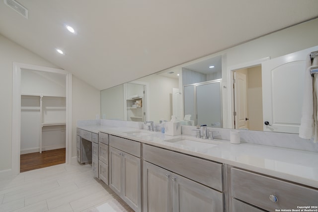 bathroom with walk in shower, double sink vanity, tile floors, and lofted ceiling