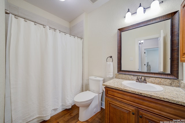 bathroom with vanity with extensive cabinet space, toilet, and hardwood / wood-style floors