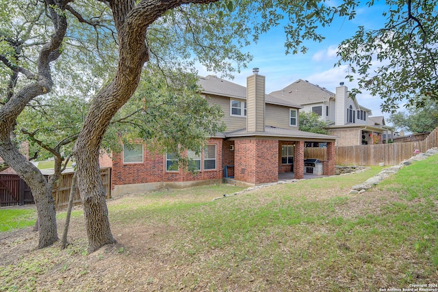 rear view of house featuring a lawn and a patio area