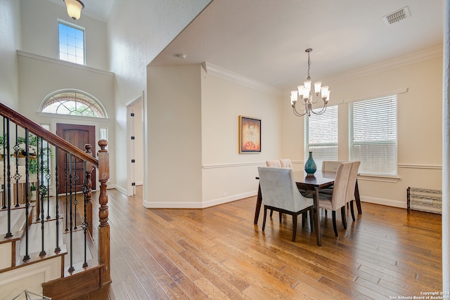 dining area with a notable chandelier, ornamental molding, and light wood-type flooring