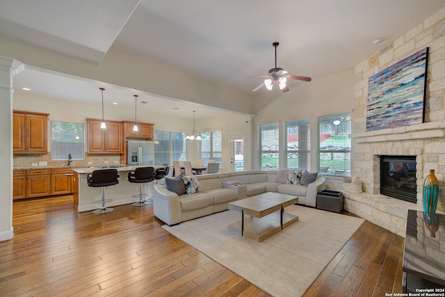 living room with hardwood / wood-style flooring, a fireplace, and ceiling fan with notable chandelier