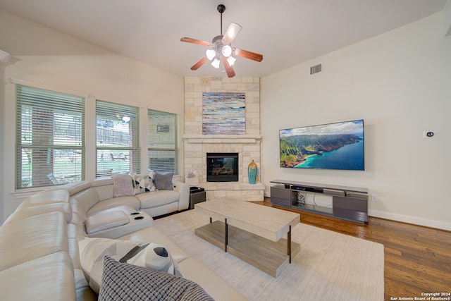 living room with hardwood / wood-style floors, a stone fireplace, and ceiling fan