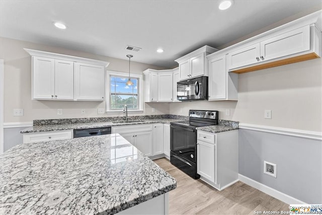 kitchen with pendant lighting, black appliances, white cabinets, sink, and light hardwood / wood-style flooring