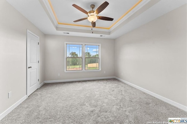 carpeted empty room featuring crown molding, ceiling fan, and a tray ceiling