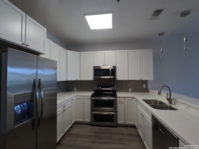 kitchen with dark hardwood / wood-style floors, backsplash, white cabinets, sink, and appliances with stainless steel finishes