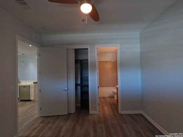 unfurnished bedroom featuring ceiling fan, ensuite bath, hardwood / wood-style flooring, and a closet