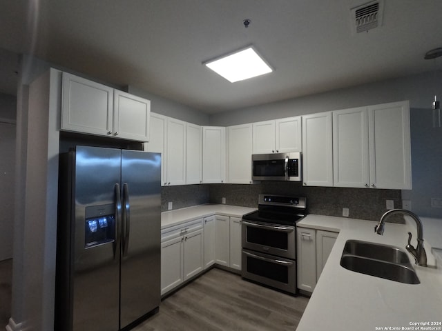 kitchen with appliances with stainless steel finishes, white cabinets, sink, and dark wood-type flooring