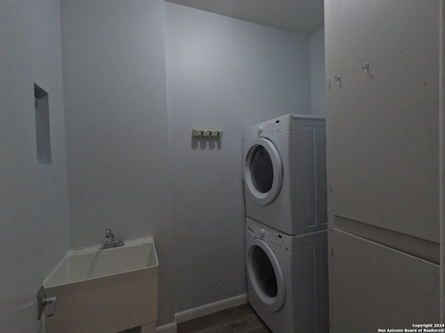 washroom with sink, stacked washer and dryer, and hardwood / wood-style floors