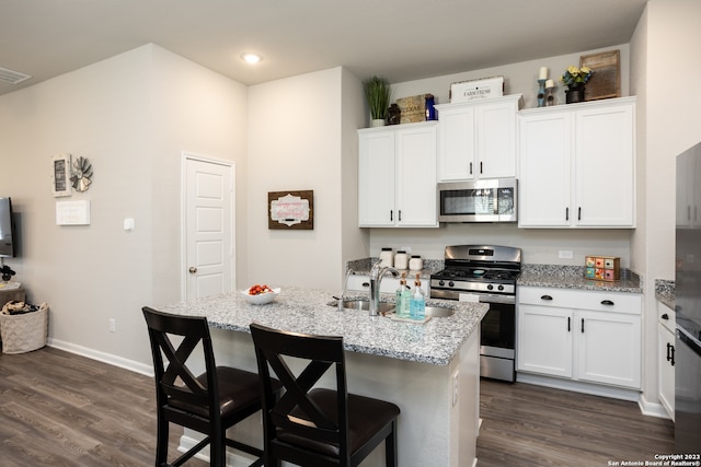 kitchen featuring a kitchen island with sink, dark wood-type flooring, a breakfast bar area, white cabinetry, and appliances with stainless steel finishes