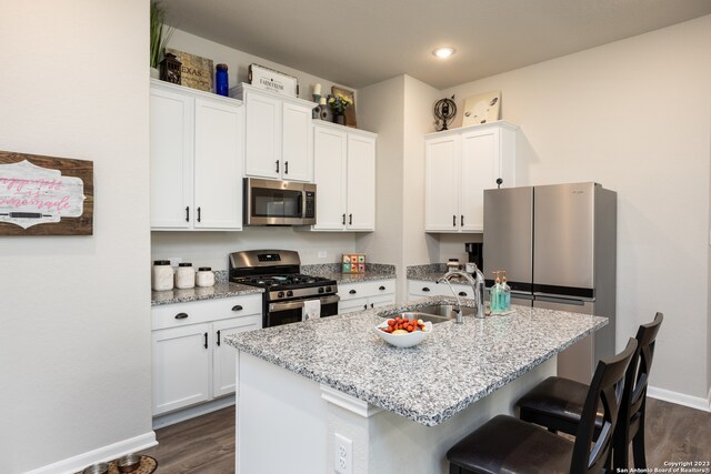 kitchen featuring a kitchen island with sink, dark wood-type flooring, white cabinets, sink, and appliances with stainless steel finishes