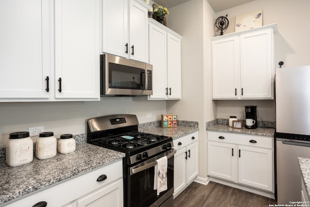 kitchen with white cabinetry, appliances with stainless steel finishes, dark hardwood / wood-style flooring, and light stone countertops