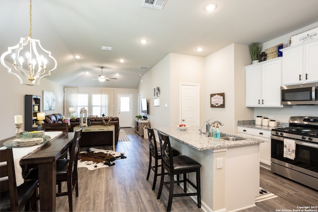 kitchen with pendant lighting, lofted ceiling, sink, hardwood / wood-style flooring, and appliances with stainless steel finishes