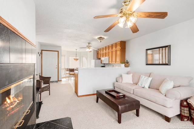 living room with light carpet, ceiling fan, and a textured ceiling