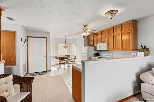 kitchen with decorative light fixtures, ceiling fan, tile countertops, white appliances, and a textured ceiling