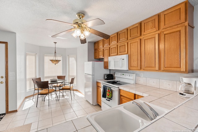 kitchen with ceiling fan, white appliances, decorative light fixtures, a textured ceiling, and tile countertops