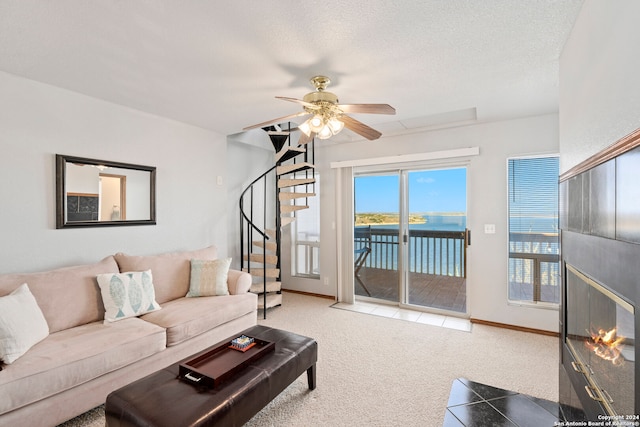 carpeted living room featuring a water view, ceiling fan, and a textured ceiling