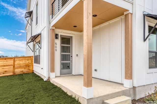 view of exterior entry featuring fence and board and batten siding