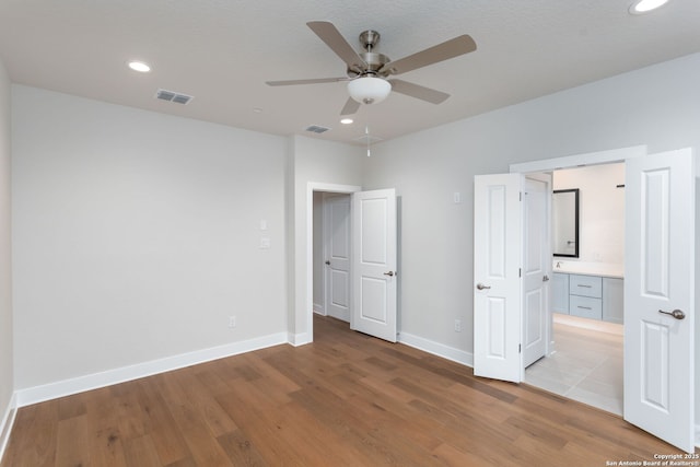 unfurnished bedroom with ceiling fan, connected bathroom, and light hardwood / wood-style floors