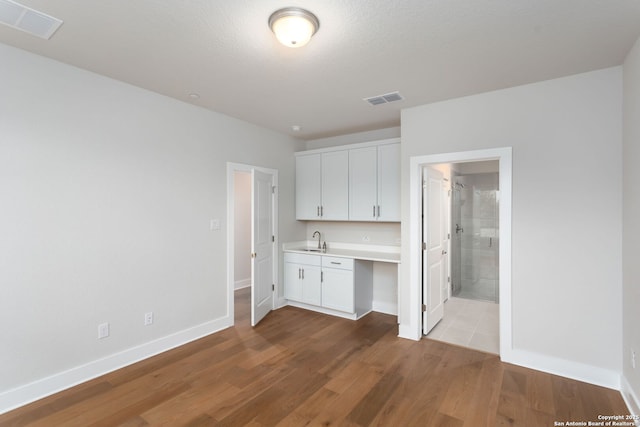 kitchen featuring sink, a textured ceiling, white cabinets, and light wood-type flooring