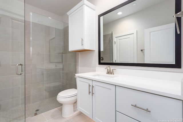 bathroom featuring tile patterned flooring, vanity, toilet, and walk in shower