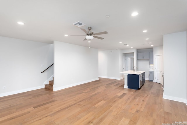 unfurnished living room with ceiling fan, sink, and light hardwood / wood-style floors