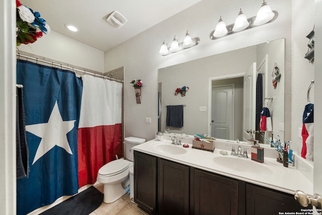 bathroom with tile floors, dual sinks, vanity with extensive cabinet space, and toilet