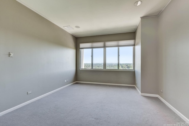 carpeted spare room featuring visible vents, baseboards, and crown molding