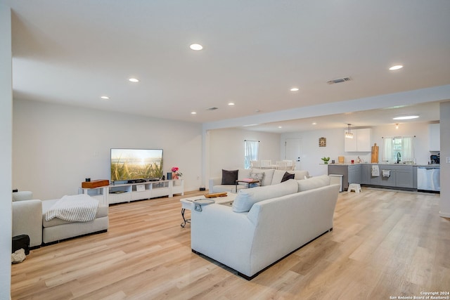 living room with plenty of natural light, sink, and light wood-type flooring